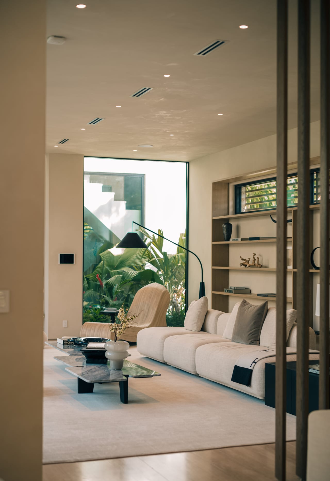 Living room viewed through steel-framed glass, with oak shelving and a low sofa