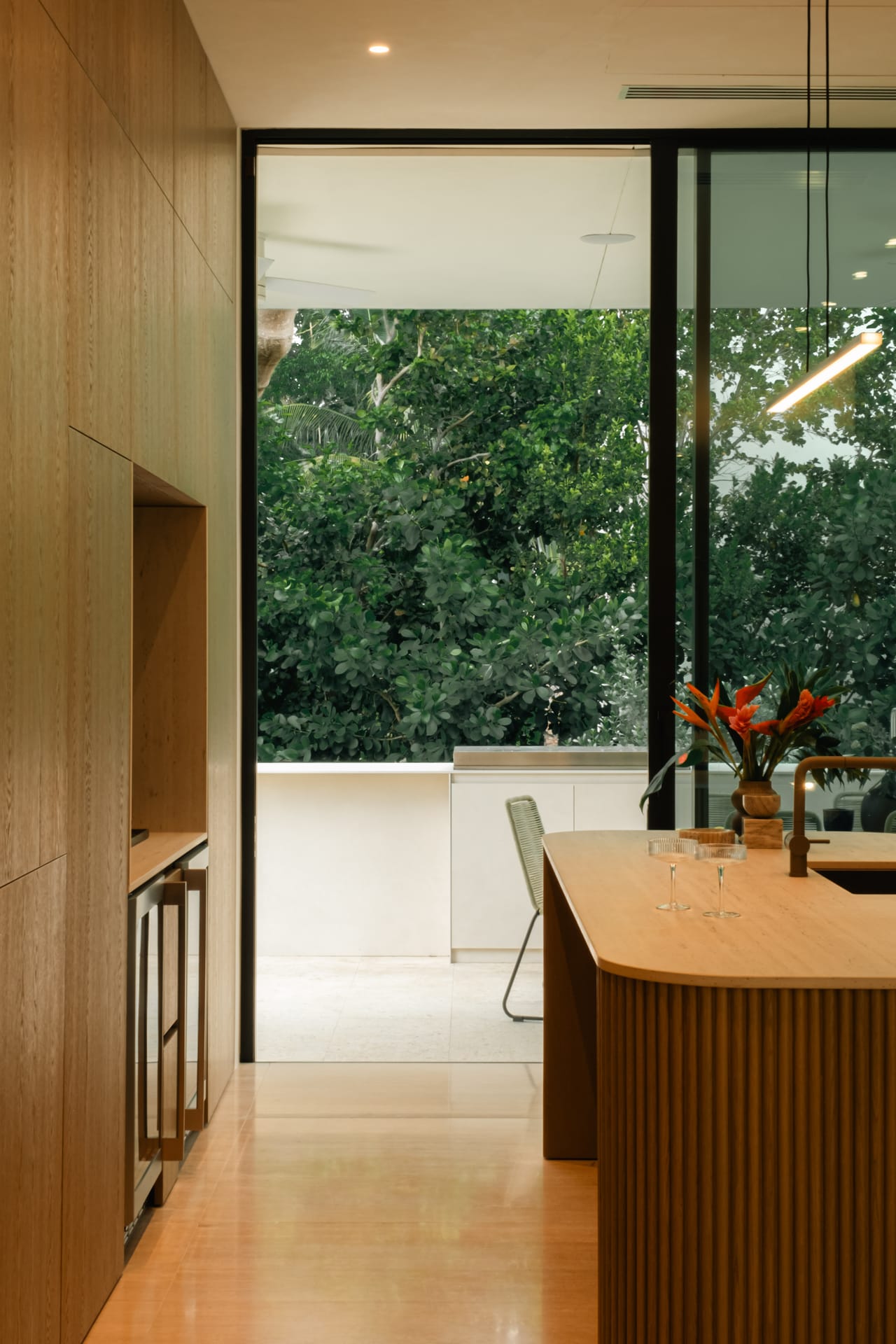 Reeded oak kitchen island with a terrace view and fresh flowers