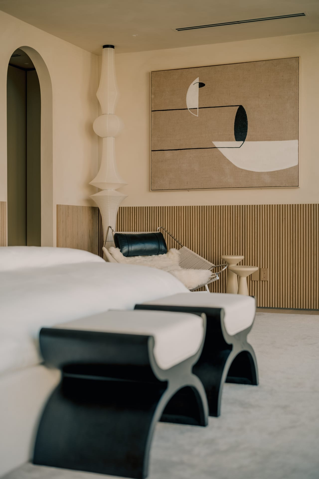 Bedroom with a reeded oak headboard wall, artwork, and sculptural benches