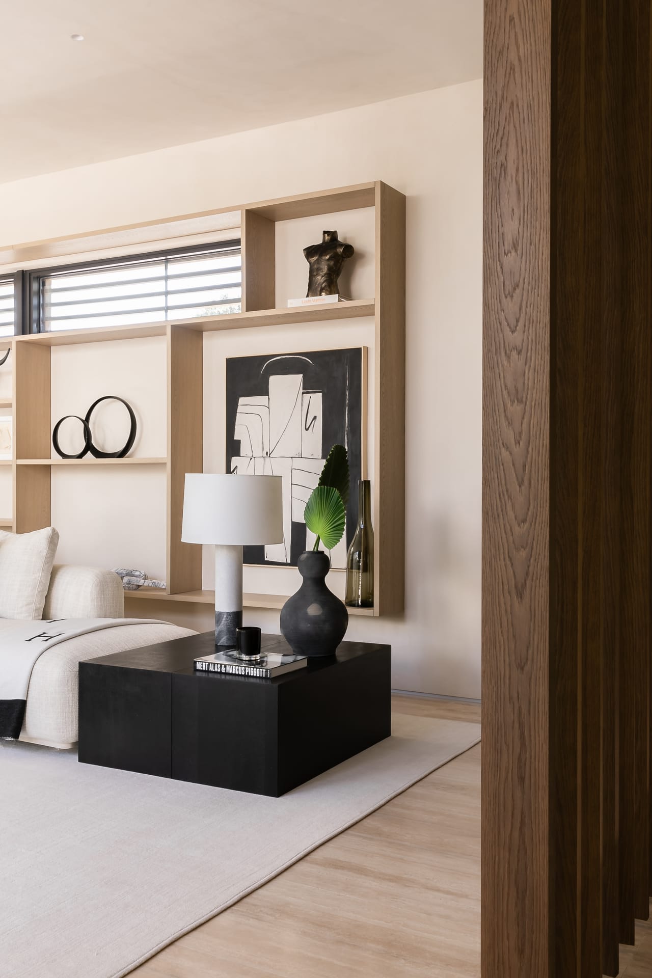 Bedroom vignette with oak shelving and a black plinth