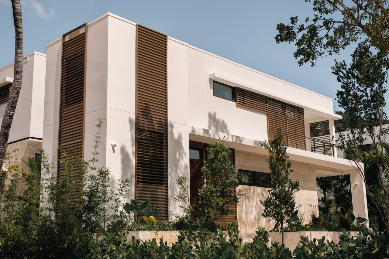 Modern villa facade in travertine and oak louvres among tropical planting