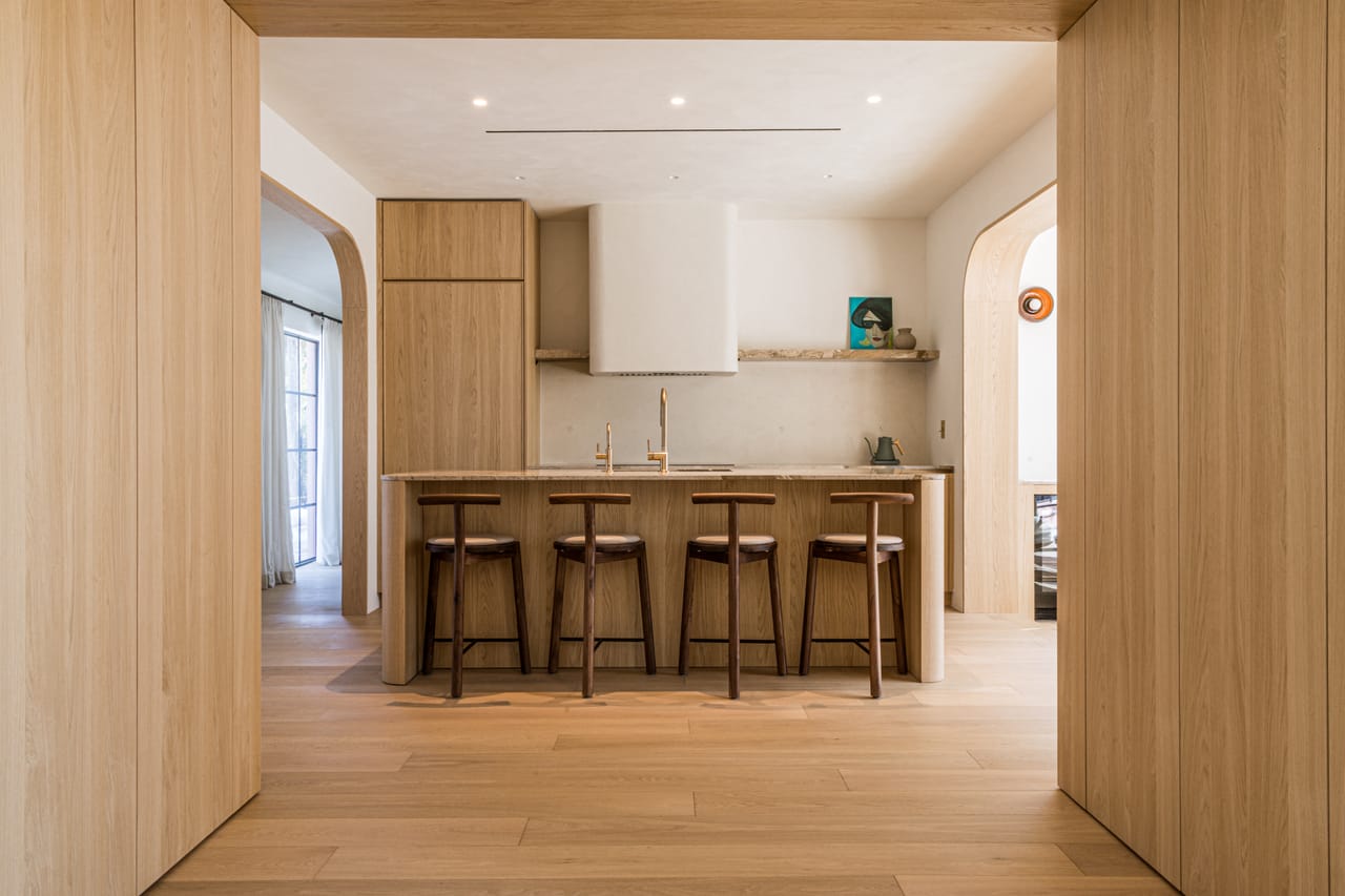 Light oak kitchen with a central island and an arched millwork opening