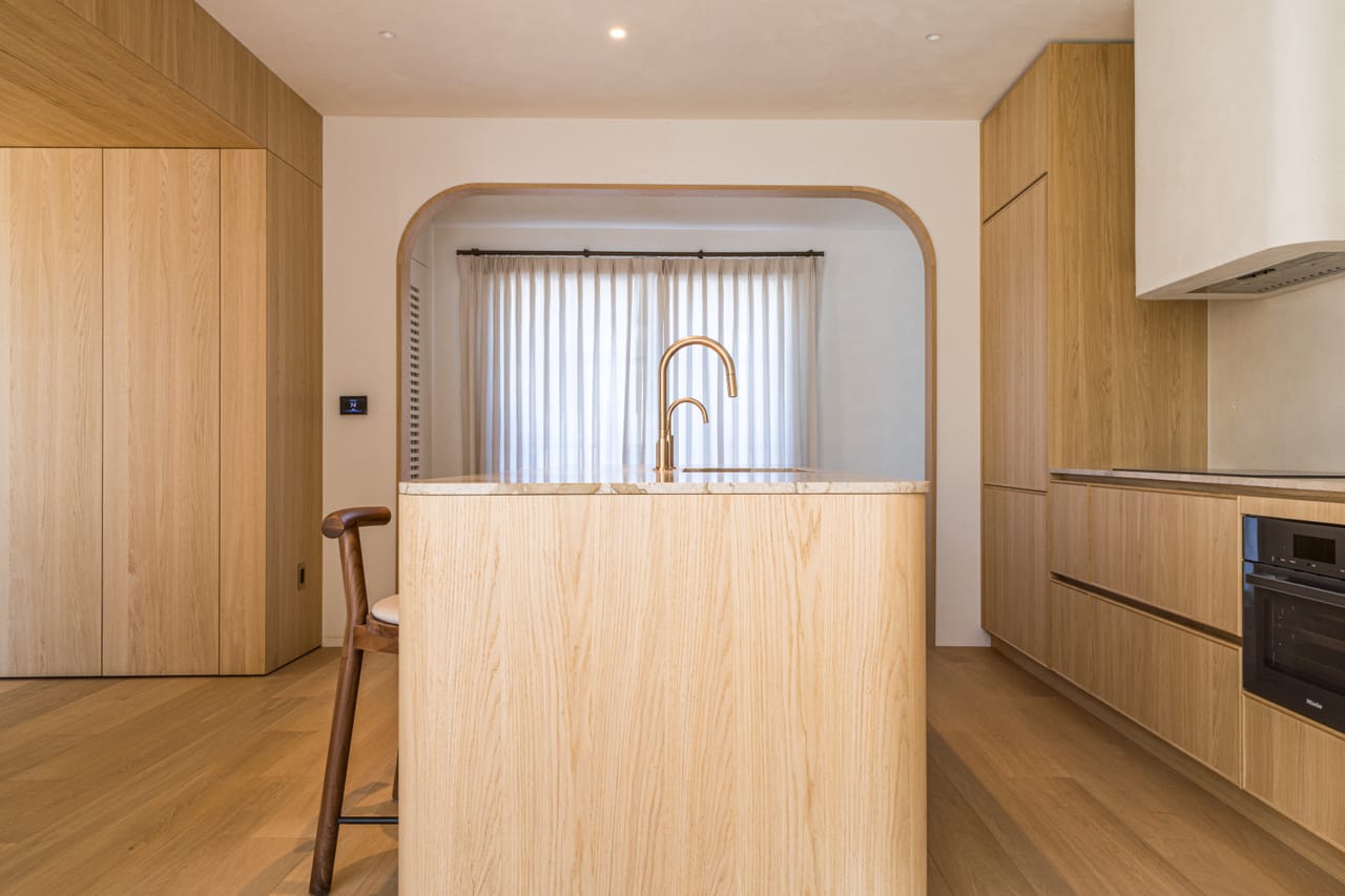 Oak kitchen island with a brass gooseneck tap and integrated cabinetry