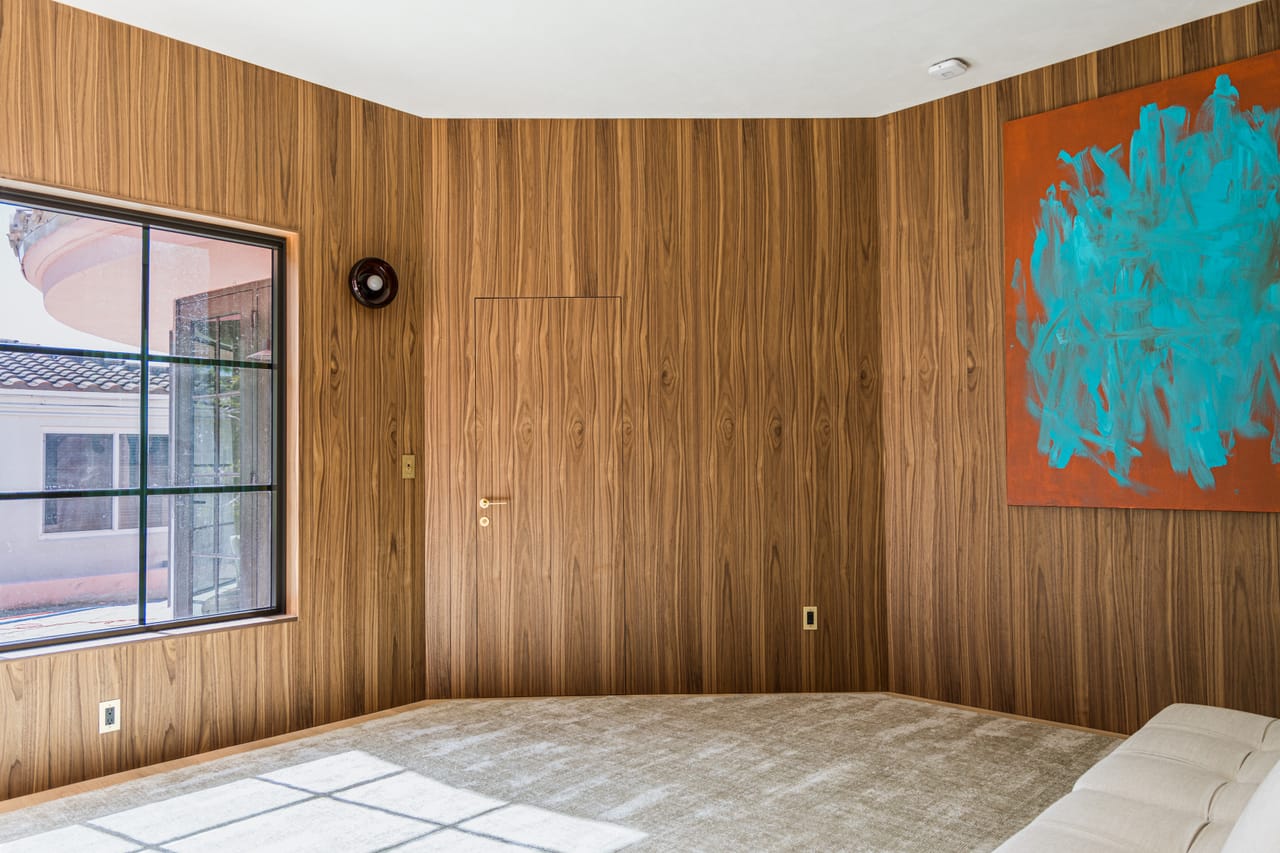 Walnut-panelled room with concealed joinery beside a casement window