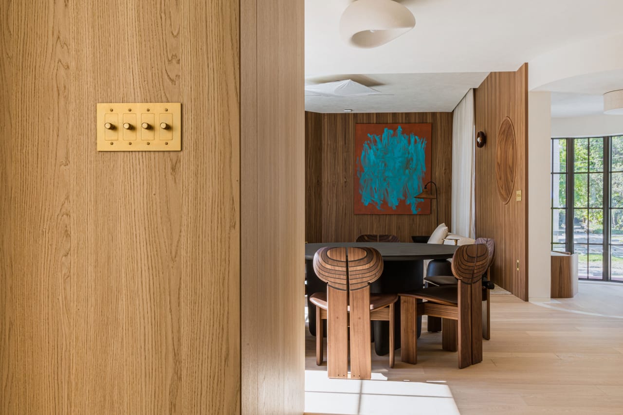 Dining area framed by walnut millwork with sculptural timber chairs
