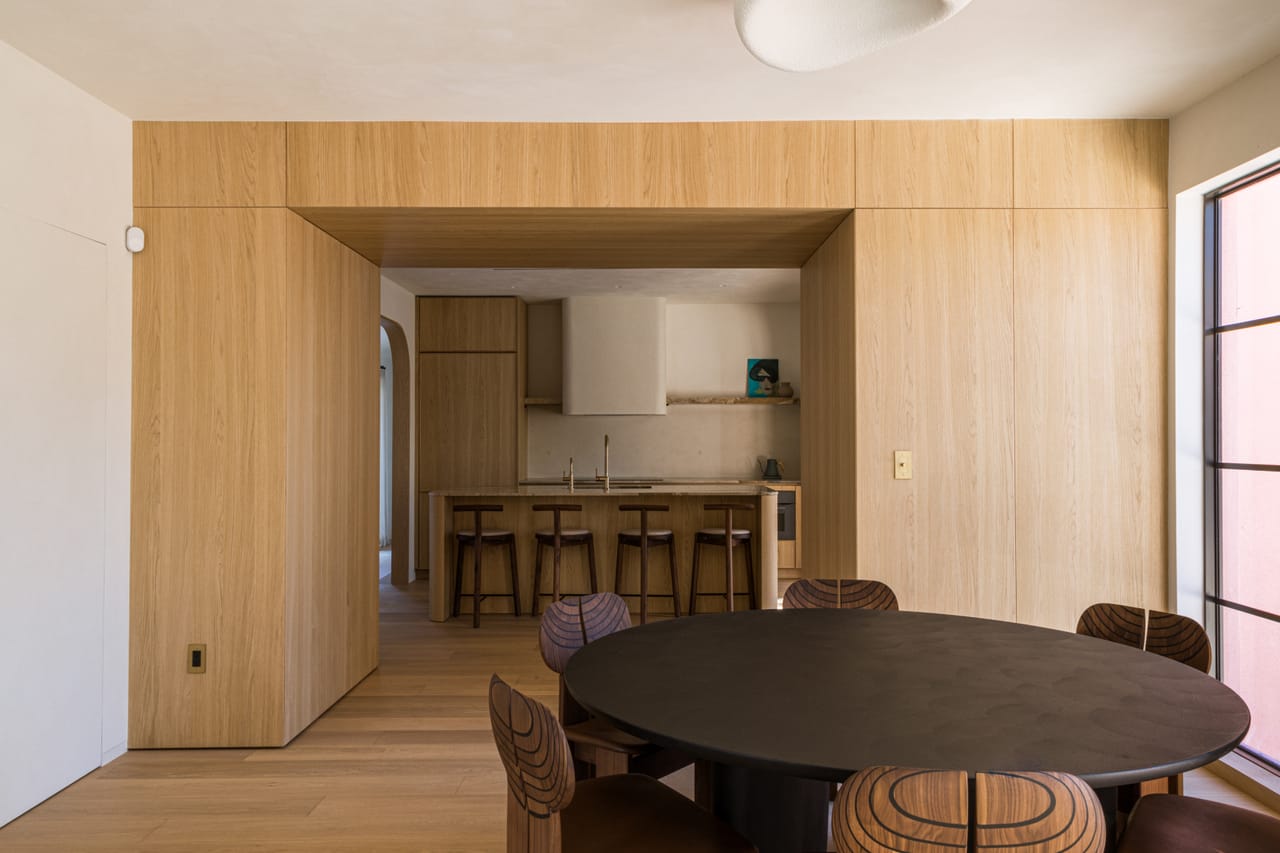 Oak-lined dining room with an oval table and a view through to the kitchen