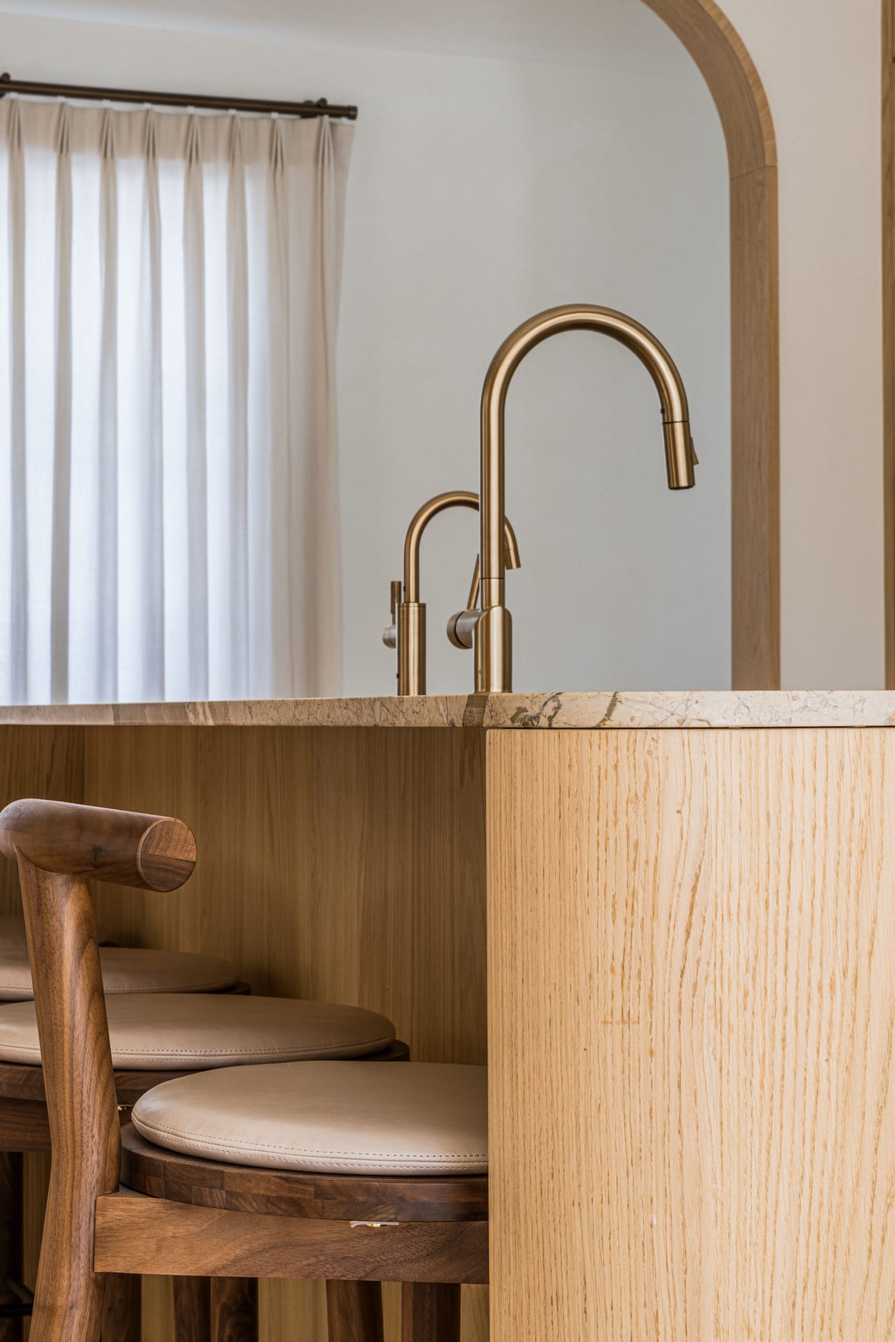 Detail of a curved oak arch and bar seating with a brass tap