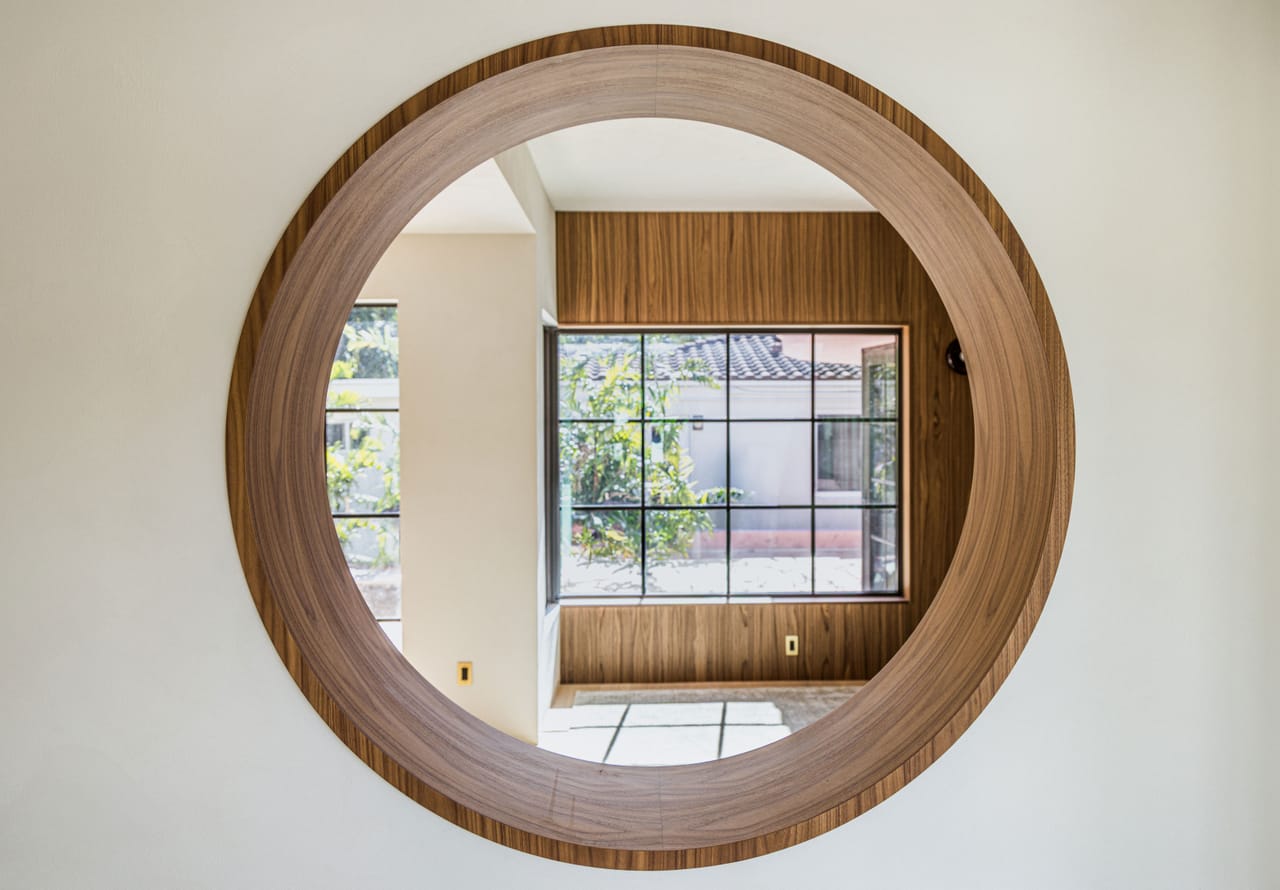 Close view of a round walnut-framed porthole window looking to the garden