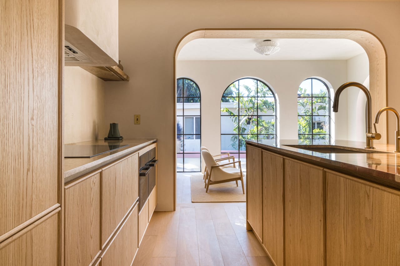 Light oak kitchen with a range hood beneath arched windows