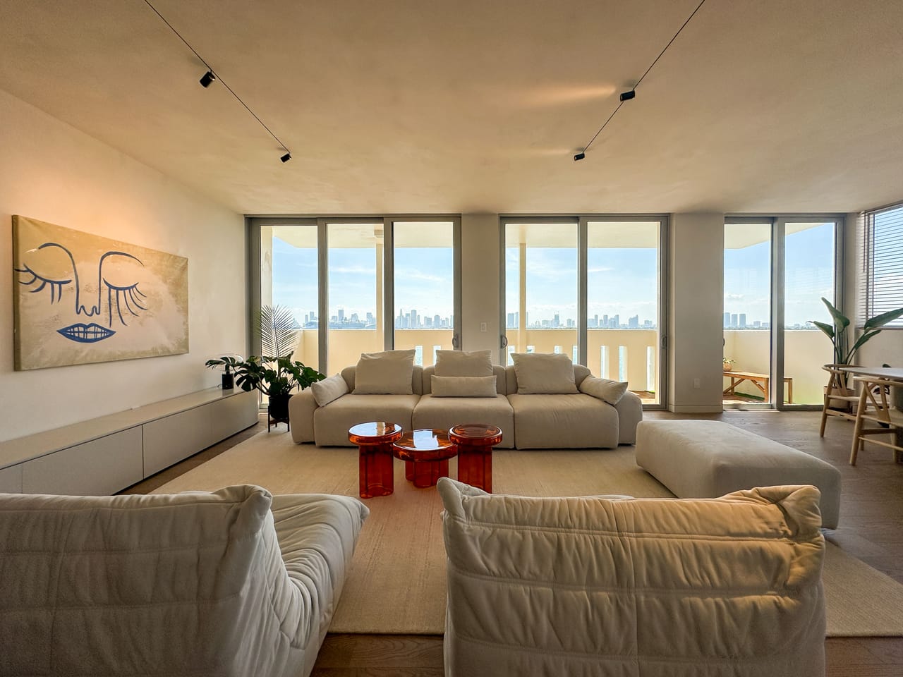 Bay-view living room with a curved ceiling, low sofas, and floor-to-ceiling glass to the skyline