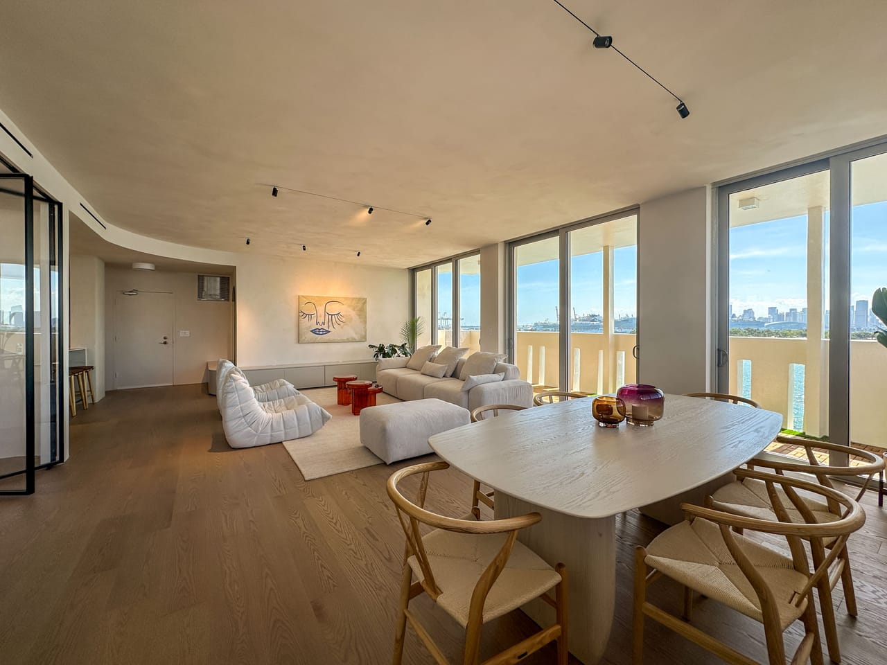 Open living and dining space with wraparound windows over the bay